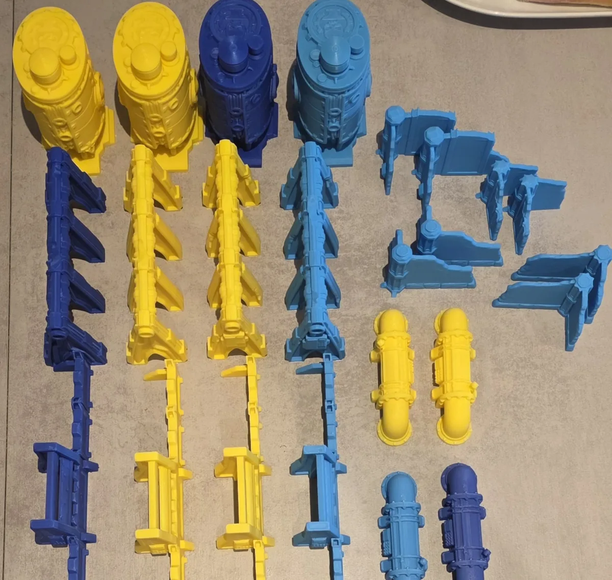 Piezas de filamento recién impresas en amarillo y azul, sin pintar